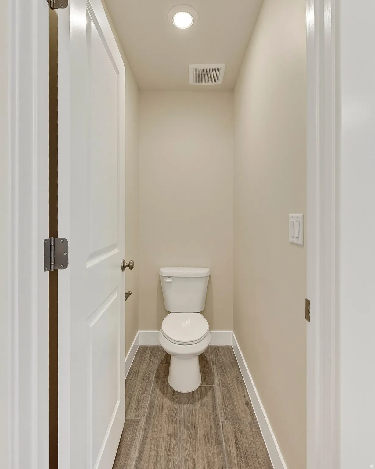 Recessed ceiling lighting, wood-finish tile flooring, and a white toilet