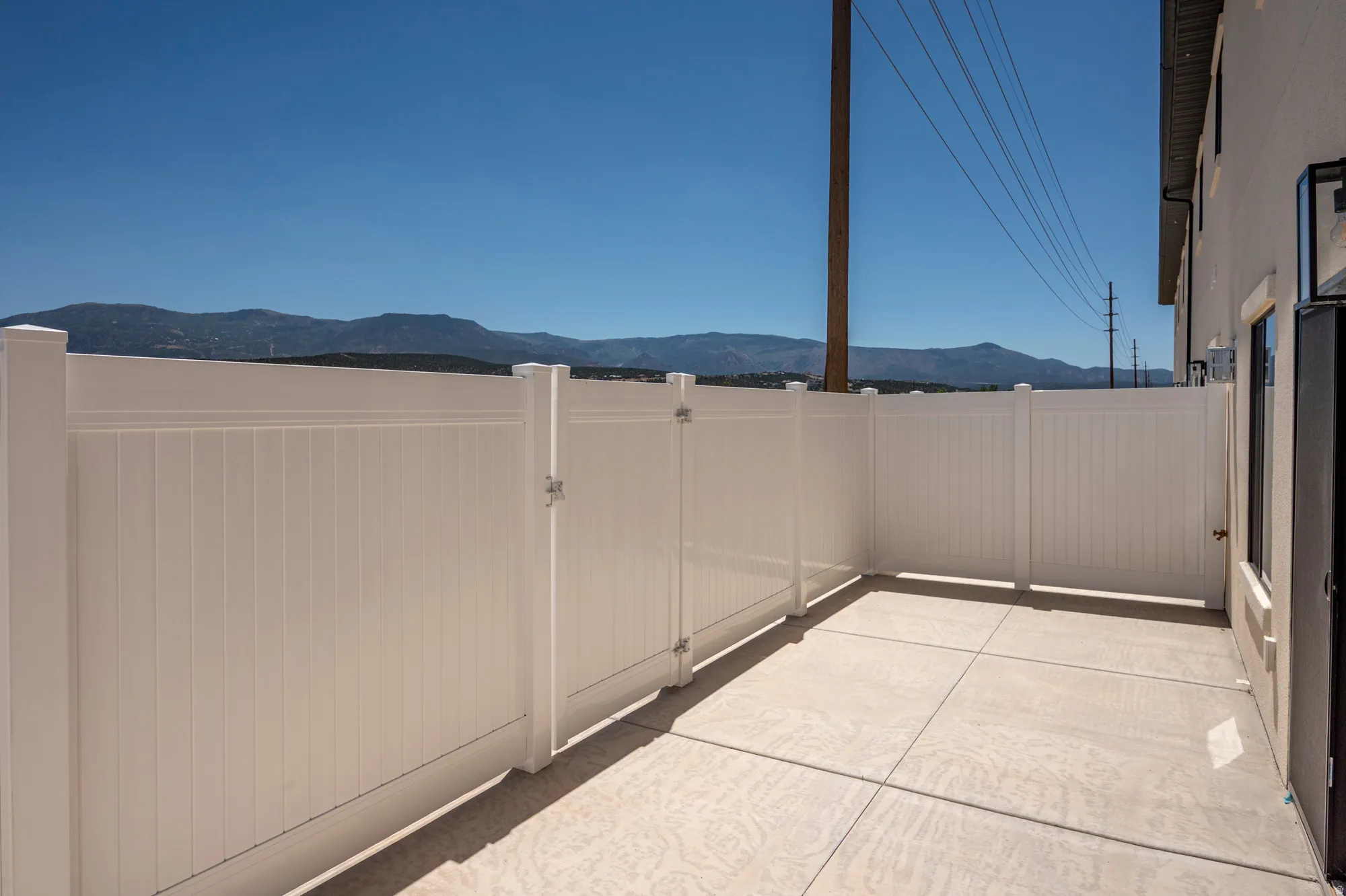 Private patio with concrete surfacing, white privacy fencing, and a secure gate