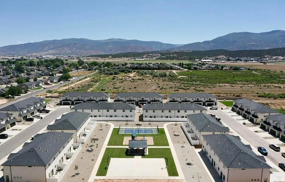 Community features multiple residential buildings with uniformly colored exteriors and dark roofing
