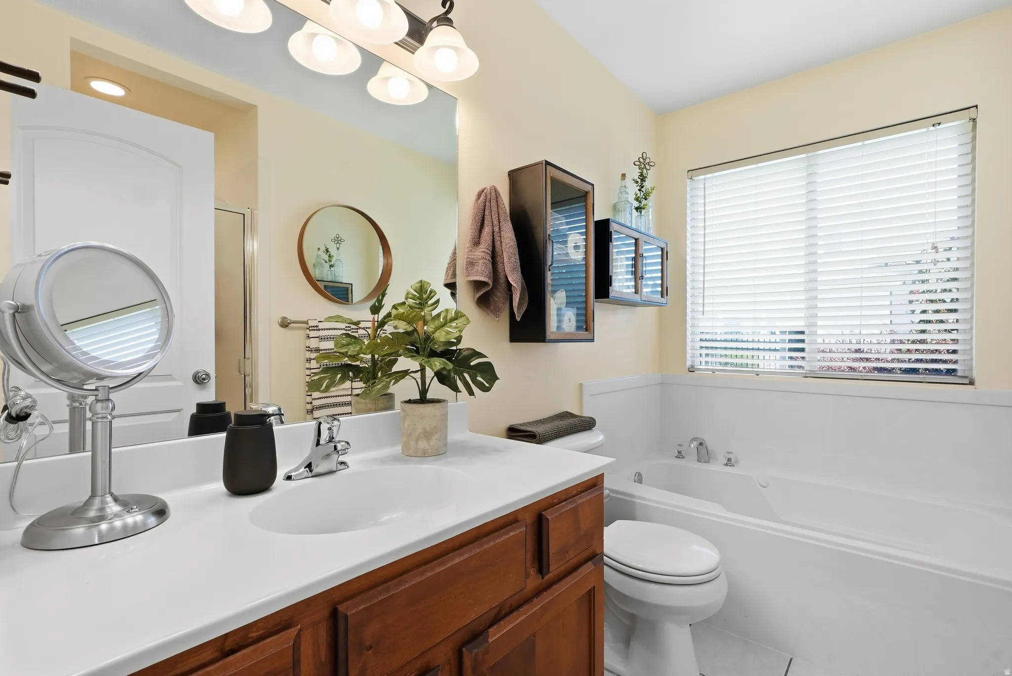 Built-in vanity with a white countertop and wood-finish cabinetry, illuminated by an overhead light fixture