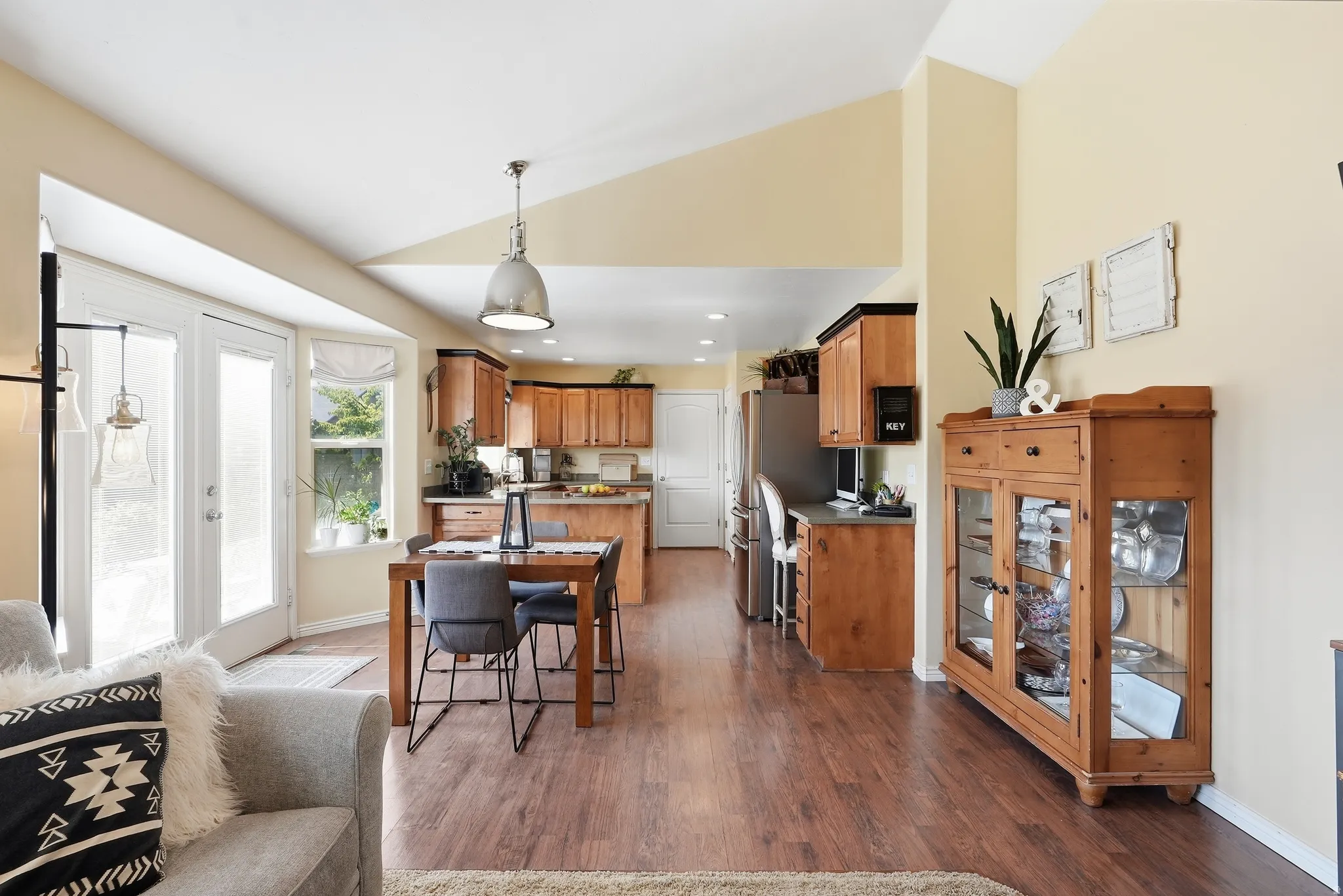 Vaulted ceilings, wood-finish flooring, kitchen with wood cabinetry, French doors, and bay window