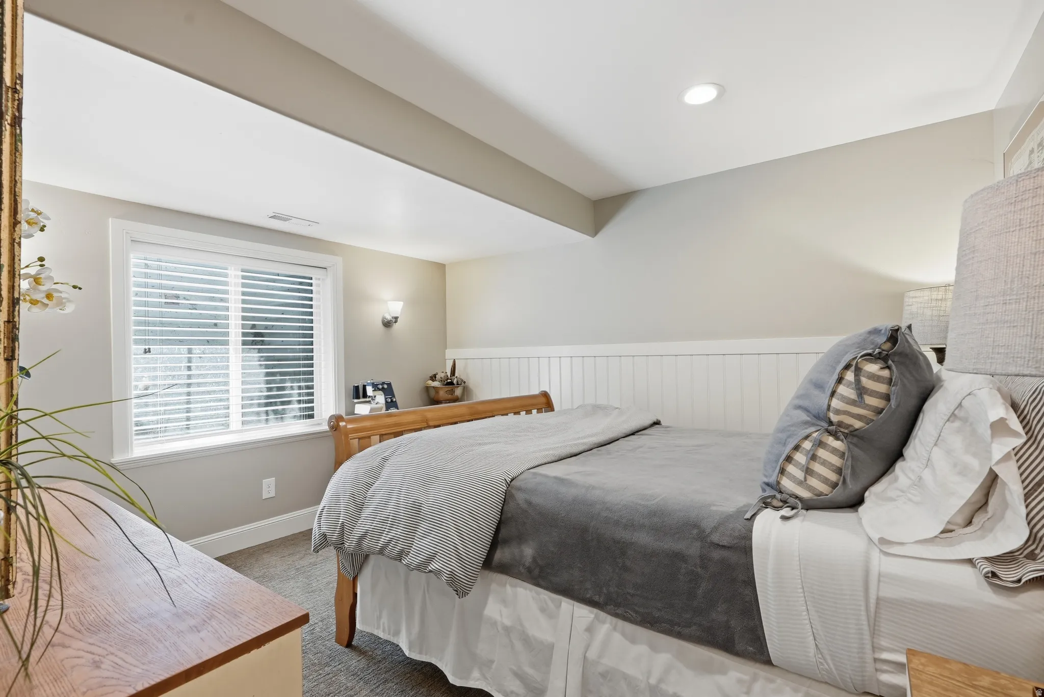 Recessed lighting, window with blinds, wall sconce, wainscoting, and carpeted flooring