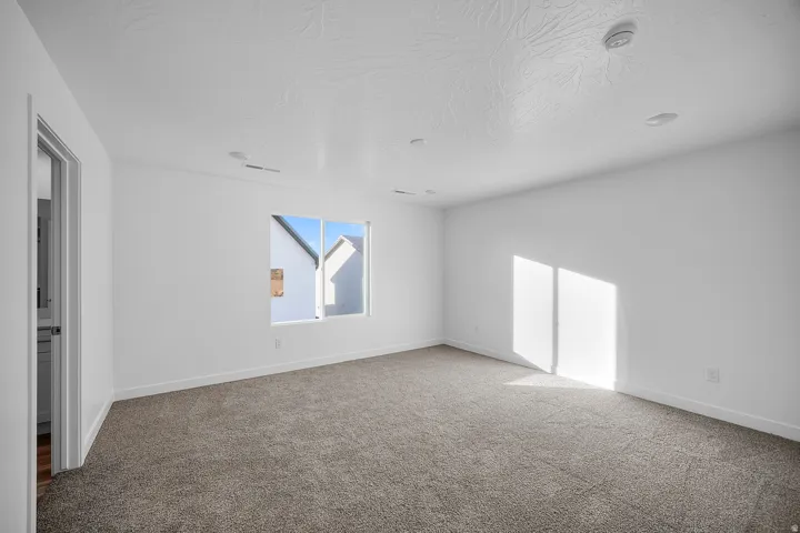 Neutral-toned carpeting, recessed ceiling lighting, and a window providing natural illumination