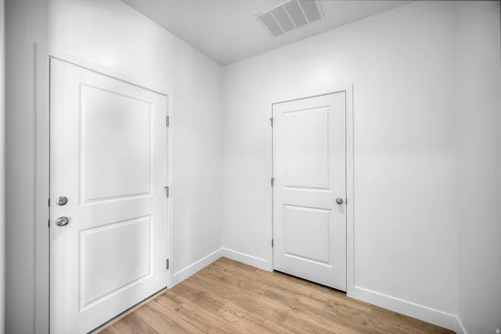 Wood-finish flooring with white baseboards and white paneled doors