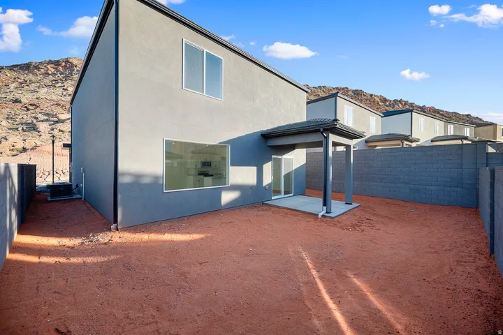 Rear exterior featuring a covered patio, sliding glass door, contemporary gray stucco siding, and privacy fencing