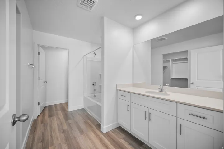 White vanity with an integrated sink, polished chrome faucet, and expansive mirror