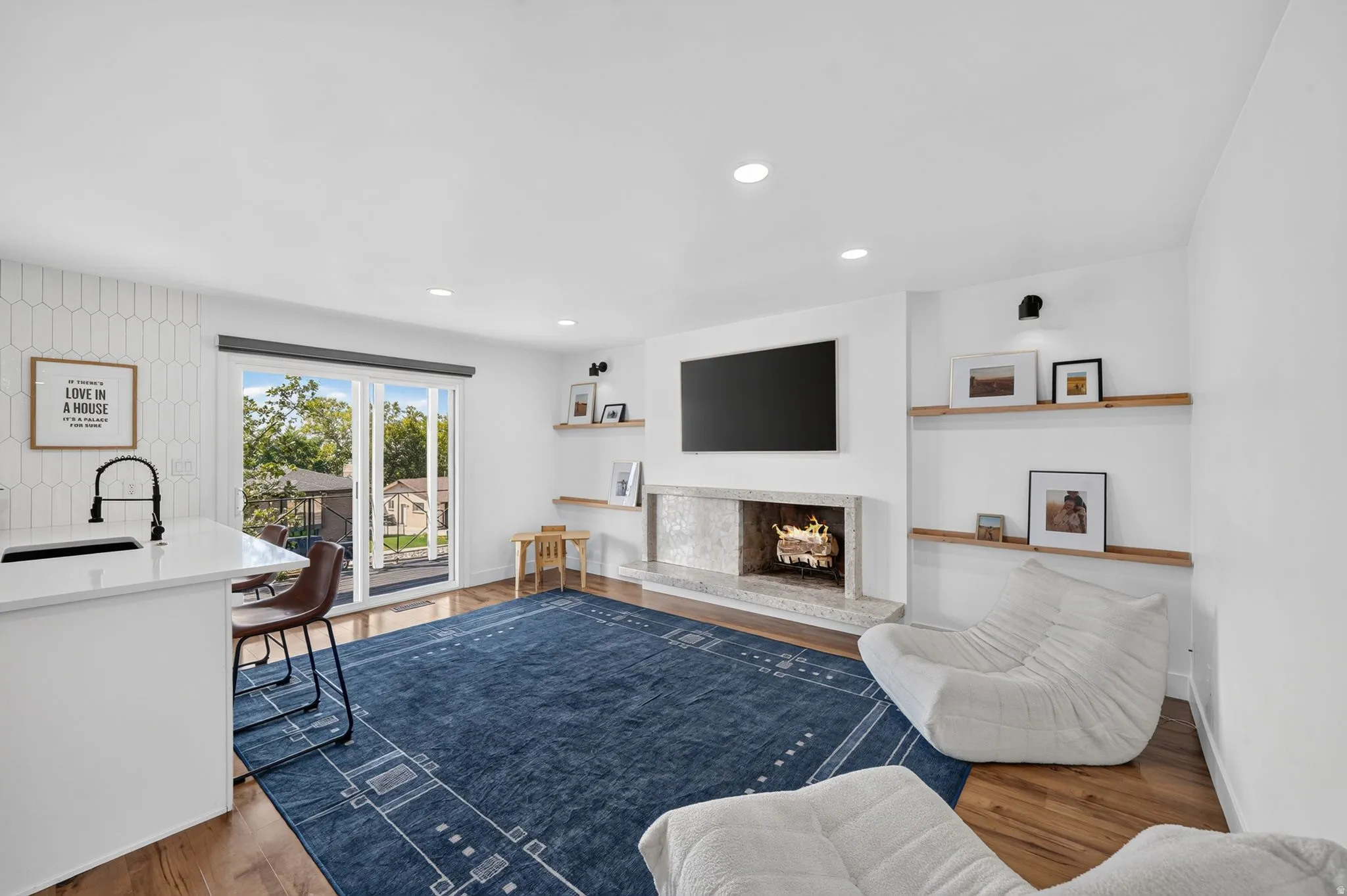 Recessed lighting, wood-finish flooring, and a fireplace with a stone surround