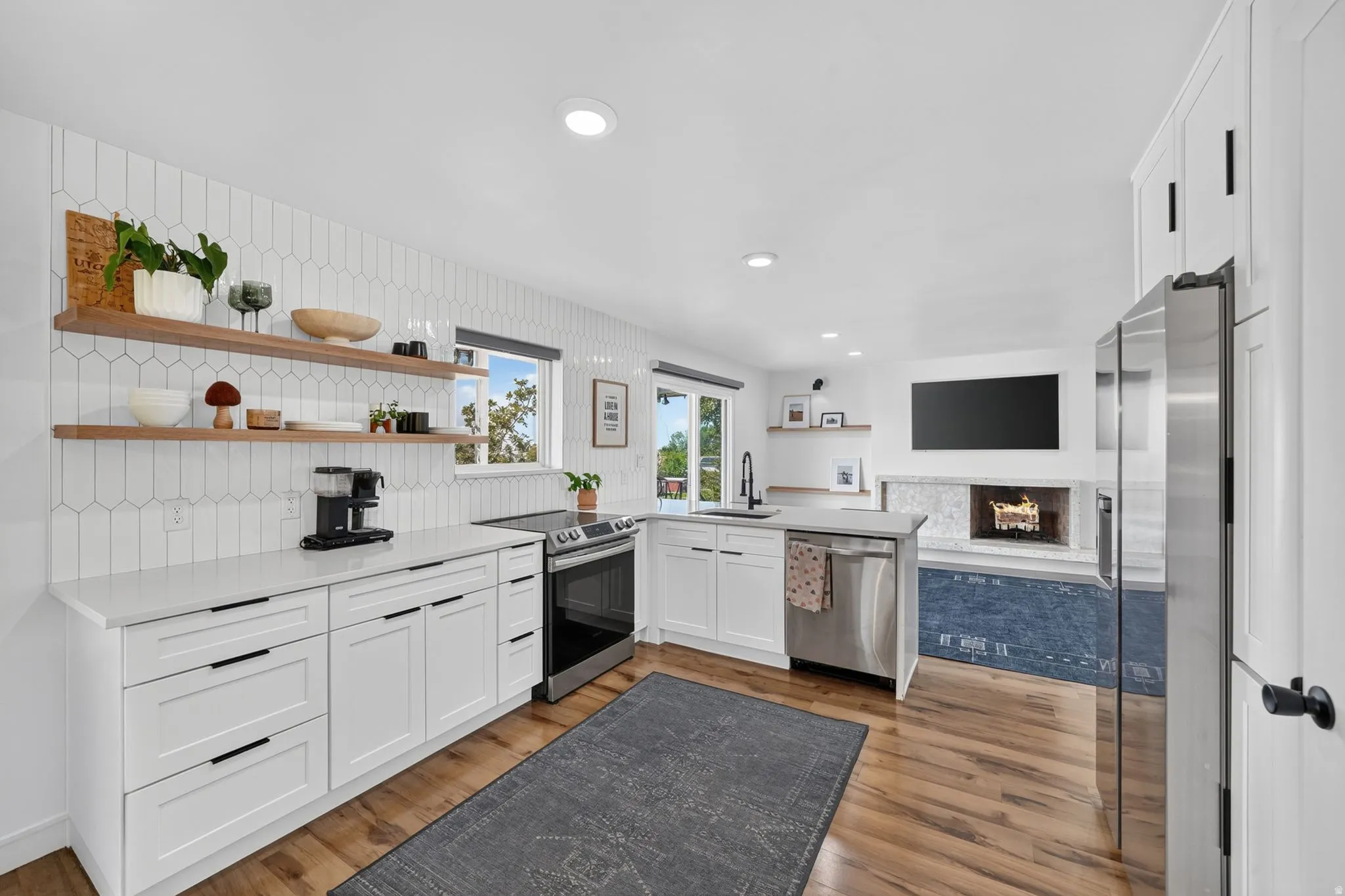 Kitchen featuring white cabinetry, light countertops, a tile backsplash, stainless steel appliances, and wood-finish flooring