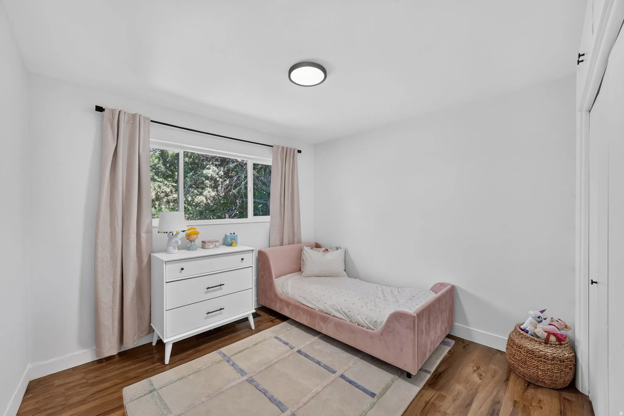 Bright bedroom with hardwood flooring, recessed ceiling lighting, and expansive multi-pane windows with natural light