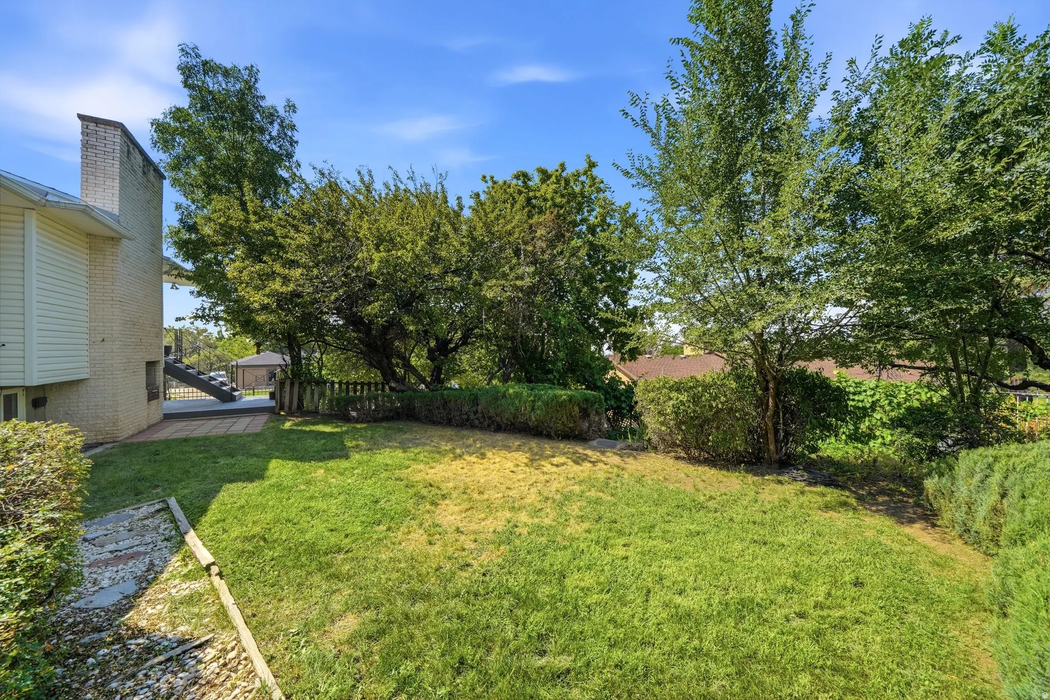 Expansive lawn area, mature trees, brick exterior, elevated deck, and a gazebo