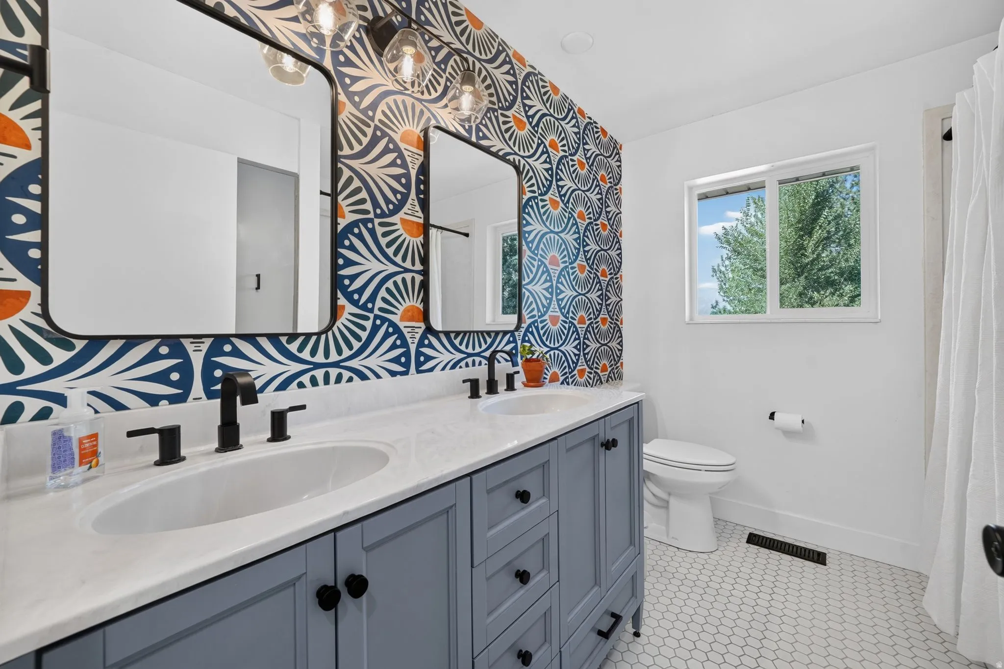 Spa-inspired primary bathroom featuring a dual-sink vanity with soft-close cabinetry, quartz countertop, and matte black fixtures