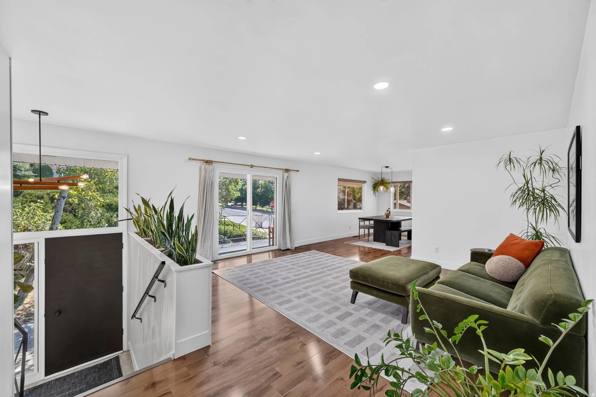 Bright, open-concept living space featuring recessed ceiling lighting, wood-finish flooring throughout, and expansive windows with natural light