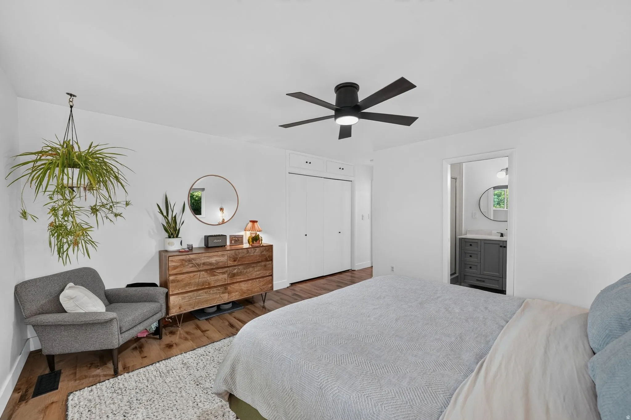 Spacious bedroom with hardwood flooring, dual beds, and ample natural light from multiple windows