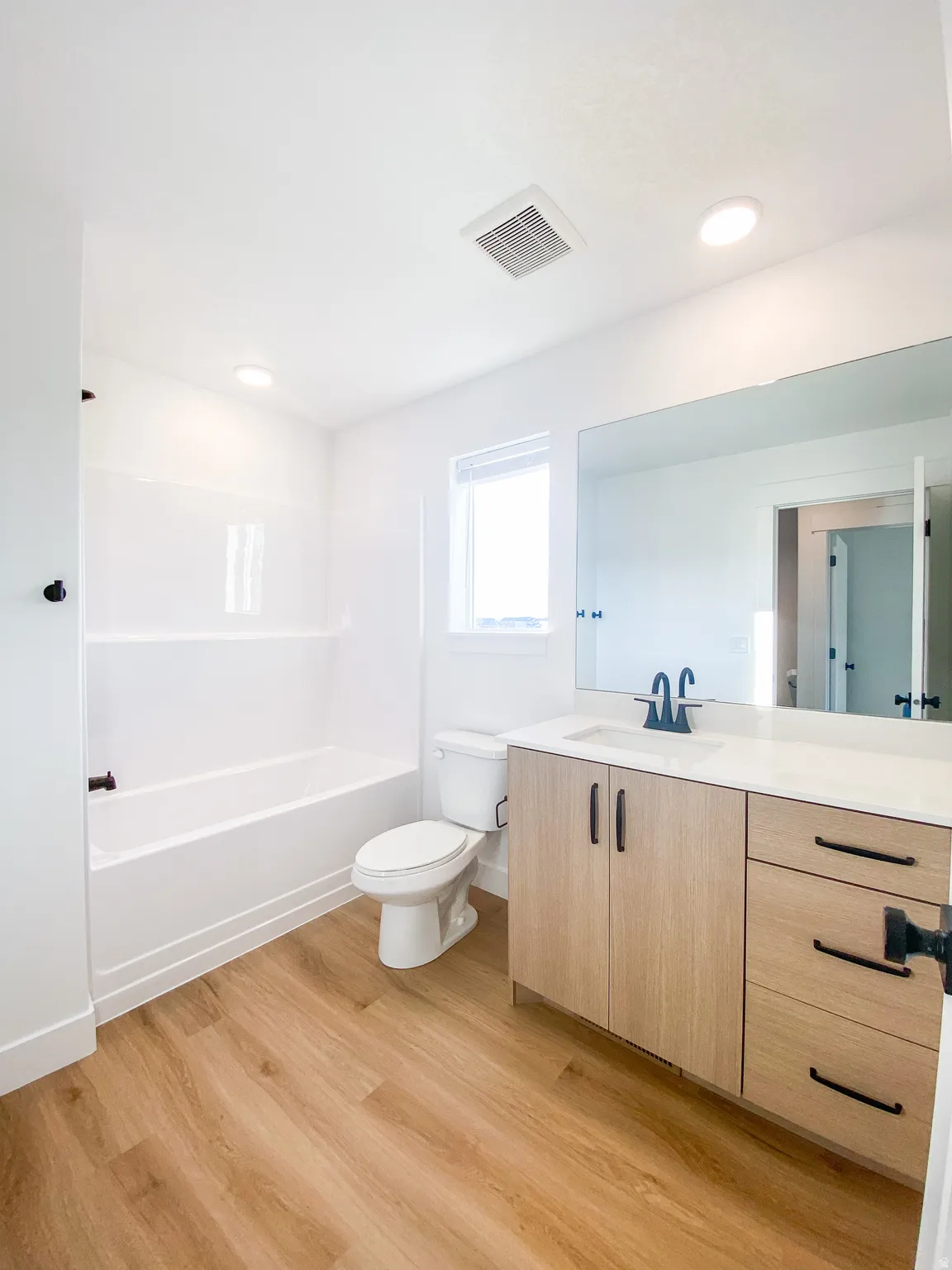 Spa-inspired primary bathroom featuring a wood-finish vanity with dual sinks, brushed nickel hardware, and ample countertop space