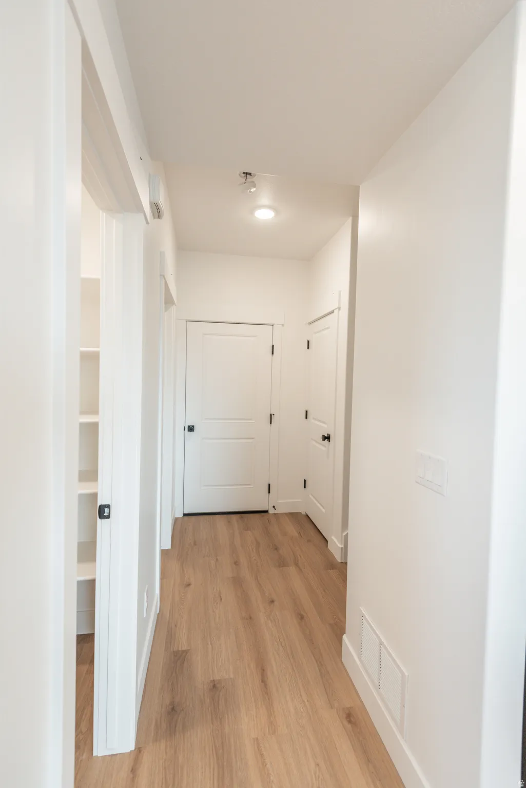 Hallway featuring wood-finish flooring, recessed lighting, and built-in shelving