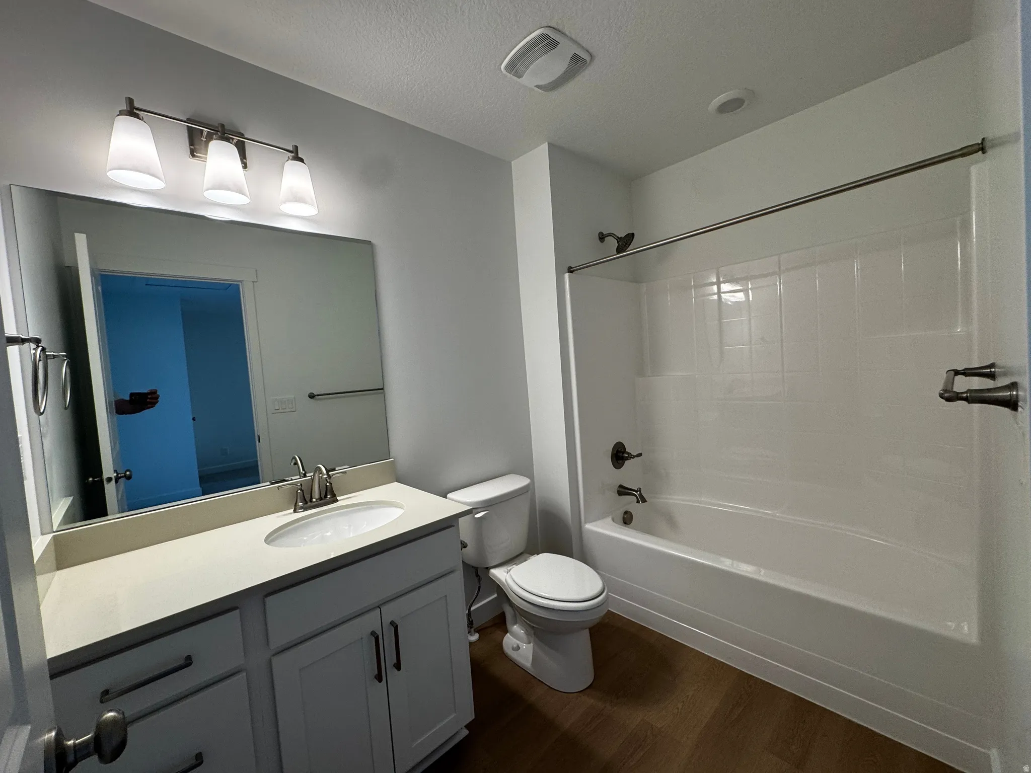 White shaker cabinetry with brushed nickel hardware, light-toned countertop, ceramic undermount sink, and wood-finish flooring