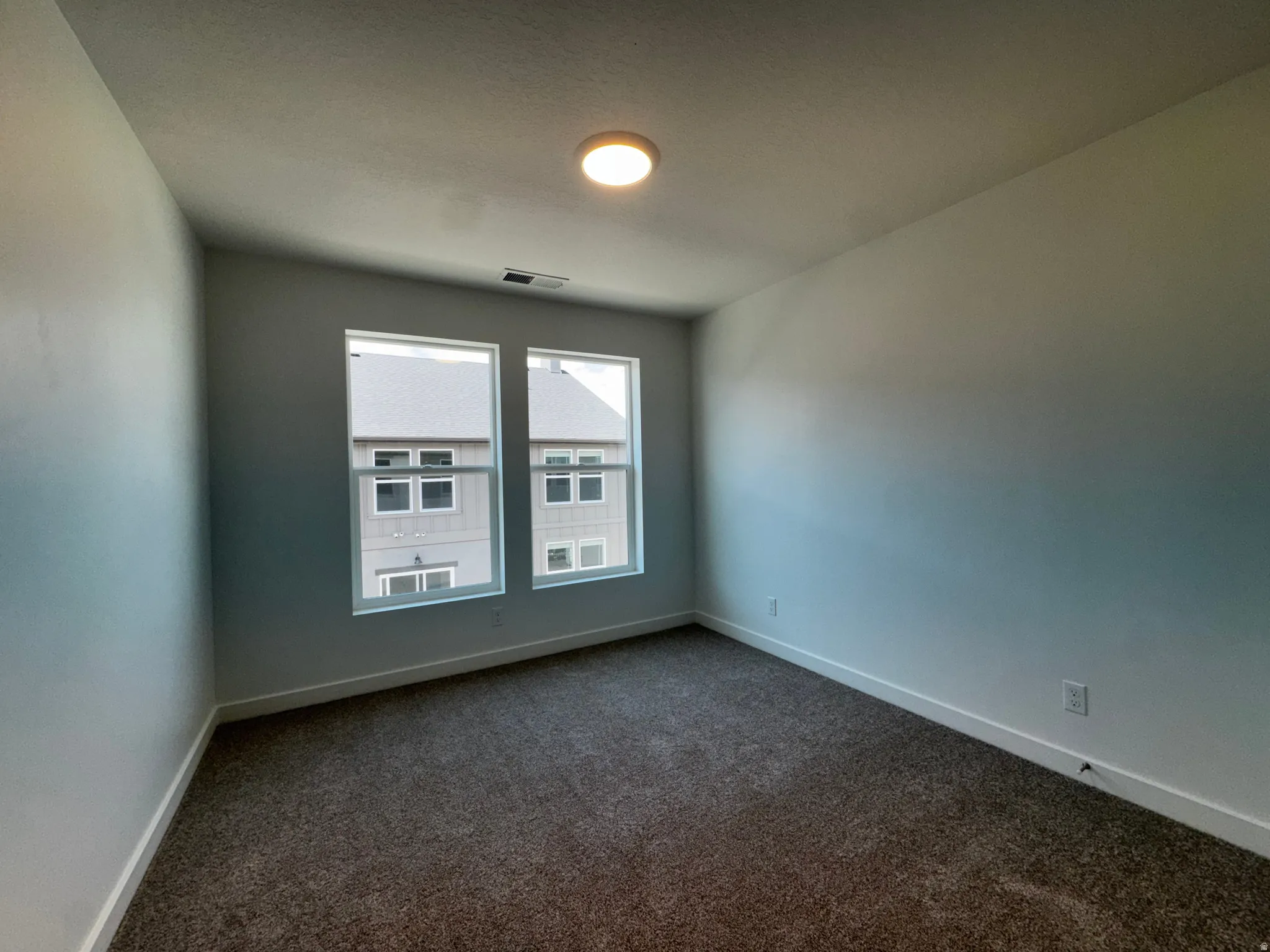 Recessed ceiling light, two windows, wall-to-wall carpeting, white wall paint, and white trim