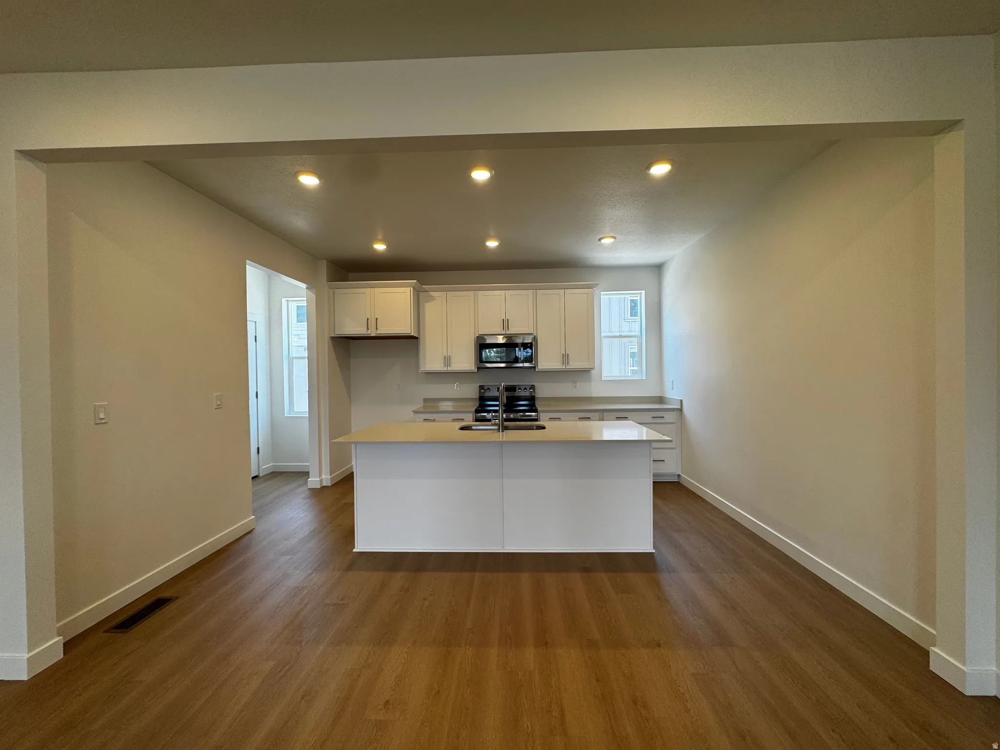 Kitchen featuring an island, white cabinetry, light countertops, stainless steel appliances, and recessed lighting