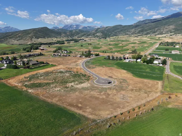 Expansive undeveloped land with a paved cul-de-sac and mountain backdrop