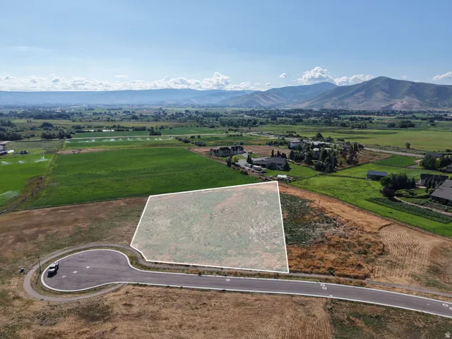 Expansive lot with mountain backdrop, surrounded by agricultural fields and residential areas