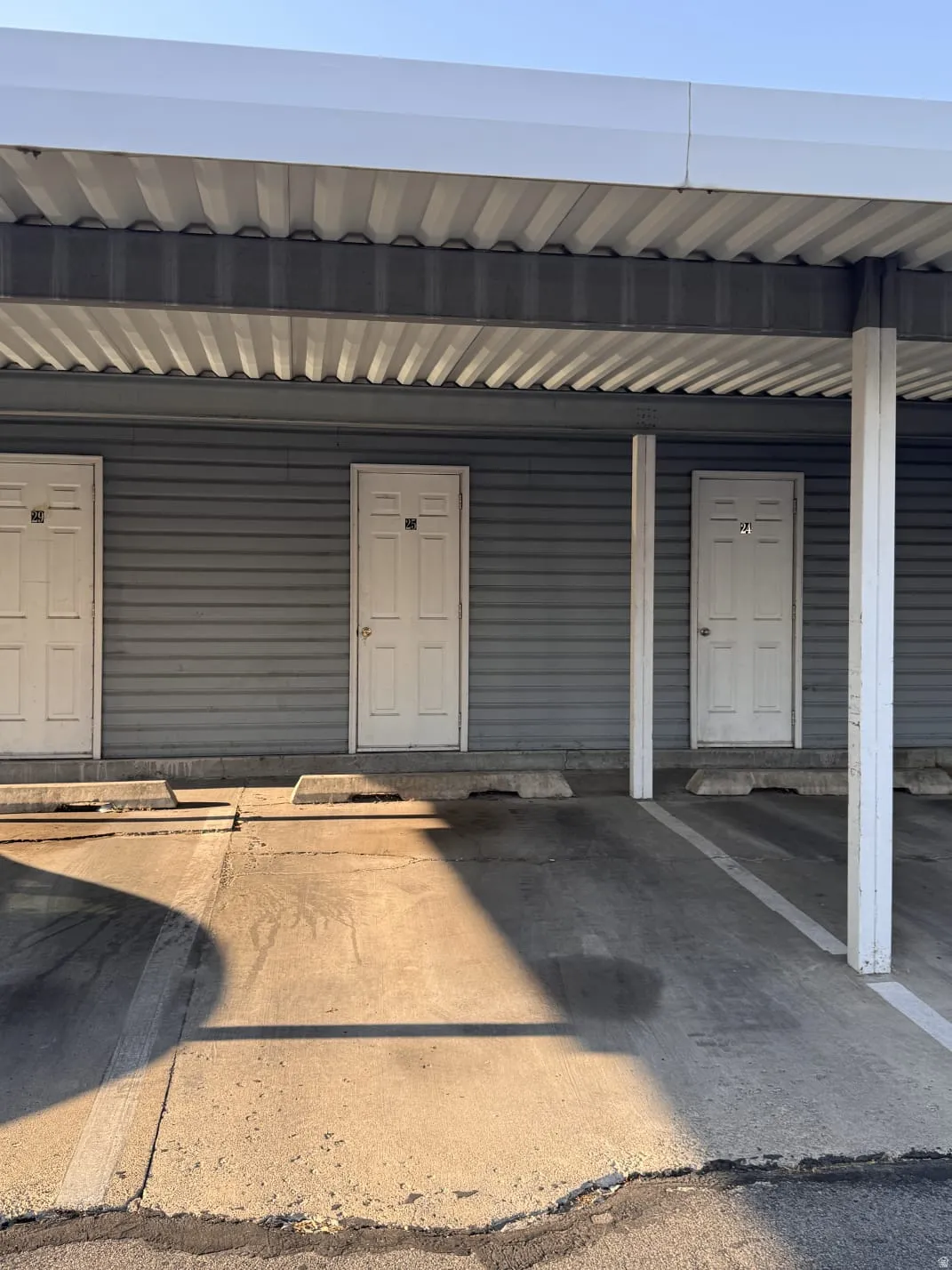 Covered parking structure with multiple parking spaces and a corrugated metal ceiling