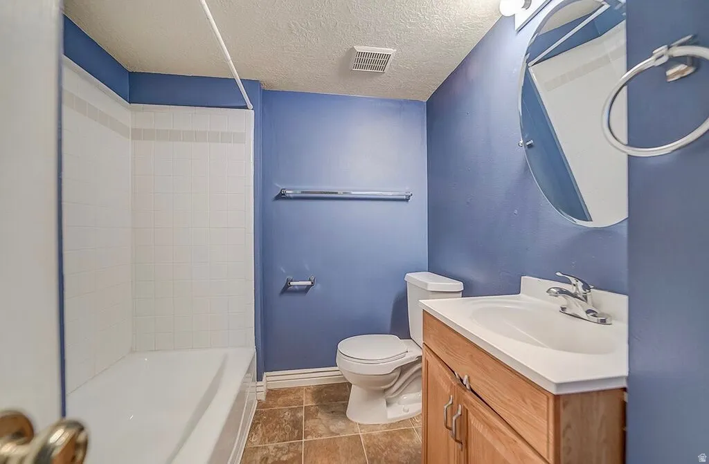 Built-in bathtub with tiled surround, wood-finish vanity with integrated sink, and a circular wall-mounted mirror