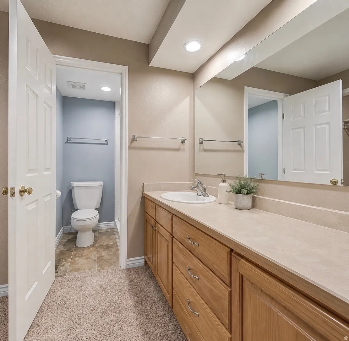 Extended vanity with integrated sink, natural wood-finish cabinetry, and full-width wall mirror