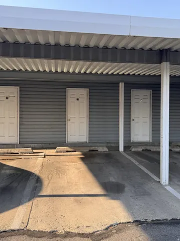Covered parking structure with multiple parking spaces and a corrugated metal ceiling