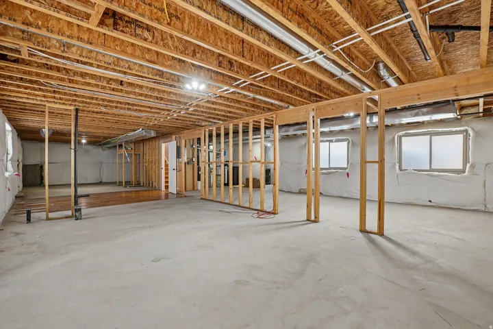 Unfinished lower level with wood framing, concrete flooring, and multiple windows
