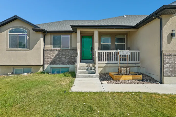 Stucco exterior with stone accents, covered entry porch, white railing, and concrete steps