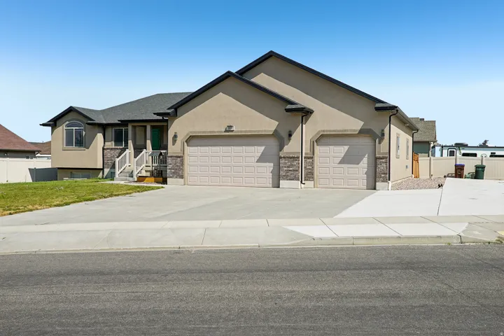 Stucco exterior featuring stone accents, a multi-car garage, and a concrete driveway