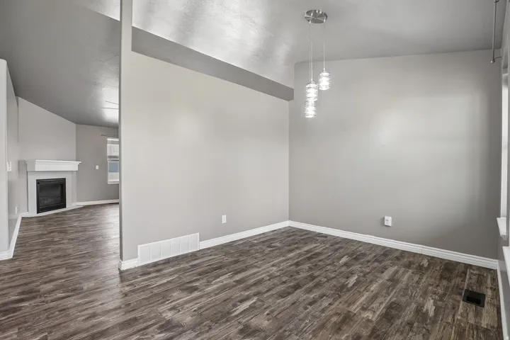 Wood-finish flooring throughout, modern pendant lighting, and a white fireplace mantel