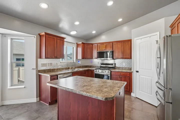 Kitchen featuring wood cabinetry, stainless steel appliances, and an island with a countertop