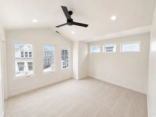 Vaulted ceiling, recessed lighting, ceiling fan, multiple windows, and light-toned carpeting
