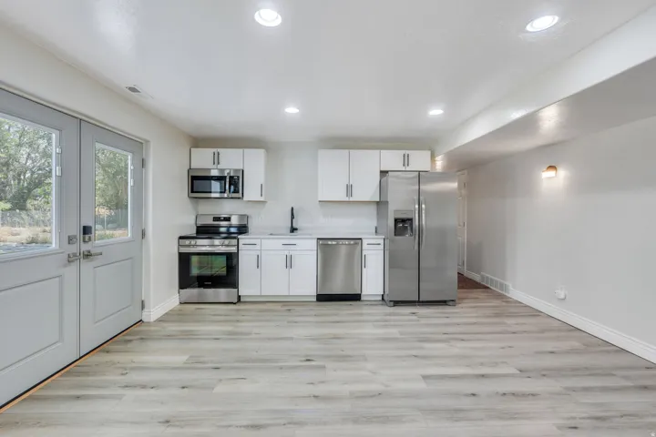Modern kitchen featuring stainless steel appliances, white cabinetry with hardware accents, and a spacious layout with recessed ceiling lighting