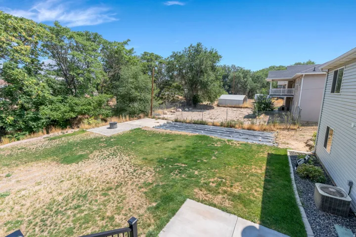 Expansive backyard featuring a concrete patio, a stone fire pit, and a grass lawn