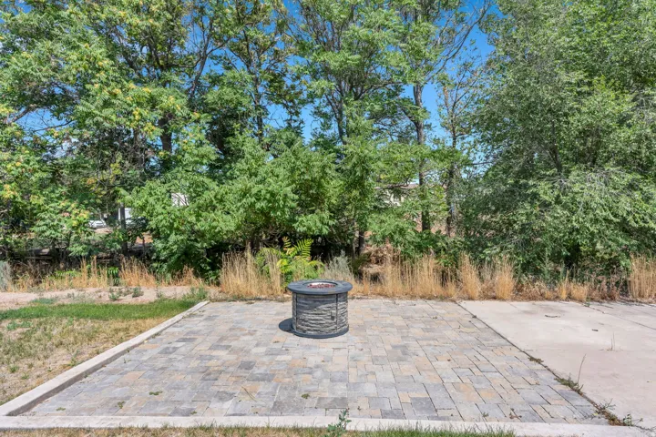 Expansive hardscaped patio featuring permeable pavers in a geometric pattern, centered with a built-in fire pit