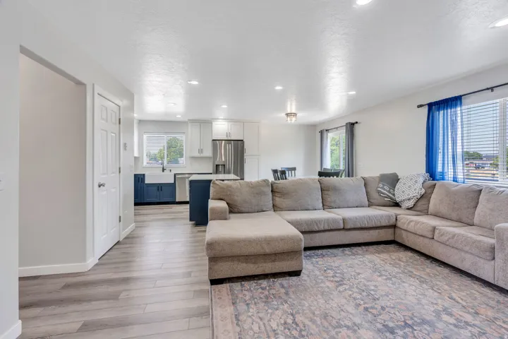Spacious open-concept living area featuring a generous sectional seating arrangement, wood-finish flooring throughout, and abundant natural light from multiple windows