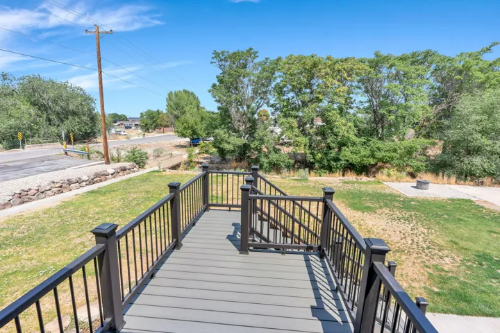 Composite deck with black aluminum railings and composite decking material, offering an elevated vantage point overlooking mature landscaping and expansive grounds