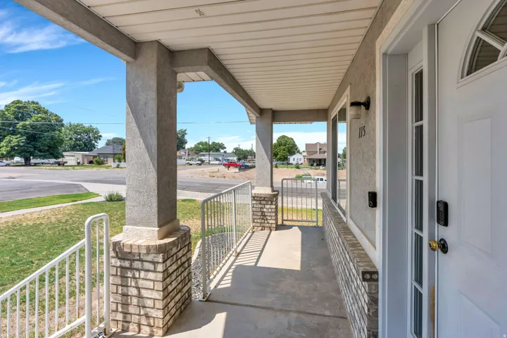 Covered front porch with concrete decking, sturdy concrete support columns, and metal railings offering a welcoming entry
