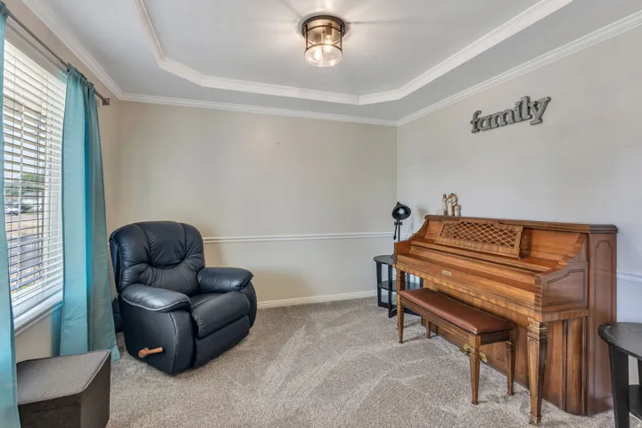 Versatile living space featuring a tray ceiling with recessed lighting, neutral wall finishes, and plush carpeting
