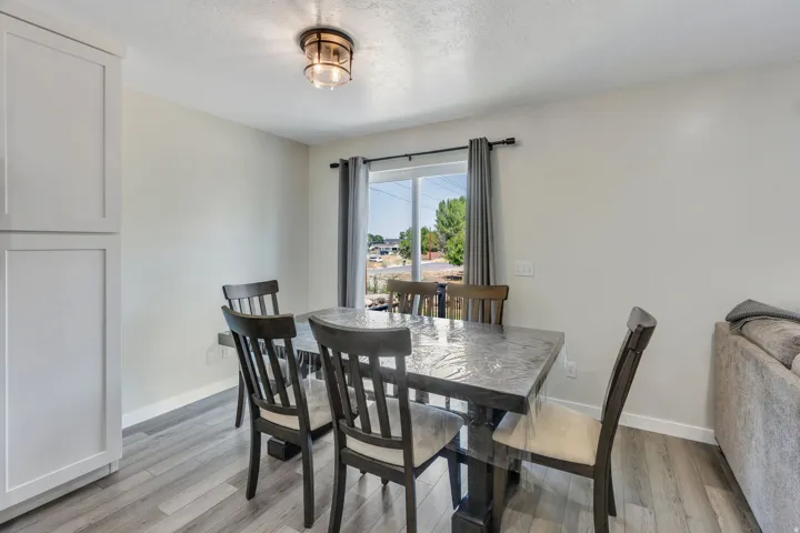 Dining room featuring a wood-finish table with seating for four, black vertical-slat chairs, and wood-finish flooring throughout