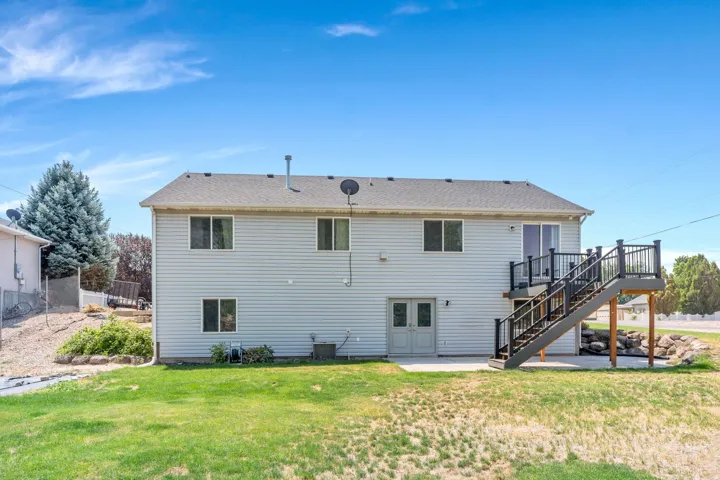 Spacious two-story home featuring white vinyl siding, multiple windows flooding interiors with natural light, and a substantial rear deck with dark railings