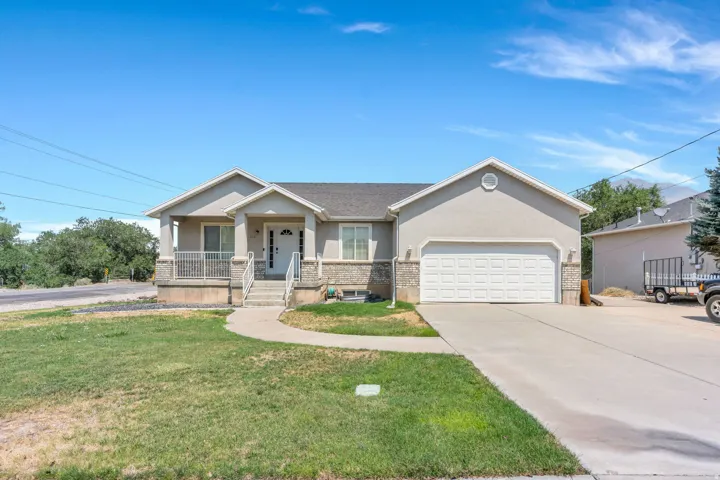 Charming ranch-style home featuring a stucco exterior with peaked roofline, front-facing covered porch with columns, and a two-car attached garage