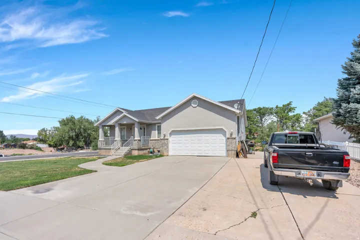 Charming single-story residence featuring a clean concrete driveway, two-car attached garage with white paneled door, and a manicured front lawn framed by mature landscaping