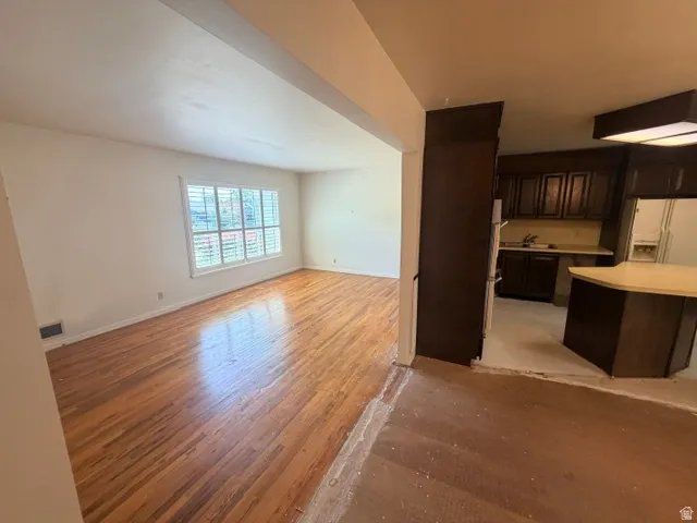Spacious interior featuring wood-finish flooring, a large window with plantation shutters, and an open concept layout.