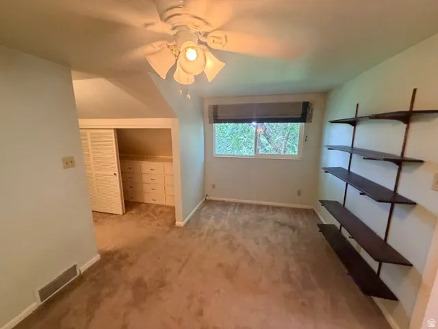 Upstairs adjoining home office ceiling fan, a window with a dark roller shade facing west, and built-in wall shelving for even more storage!