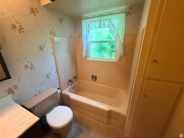 Bathroom featuring a window over the tub, tiled surround and built-in cabinetry.
