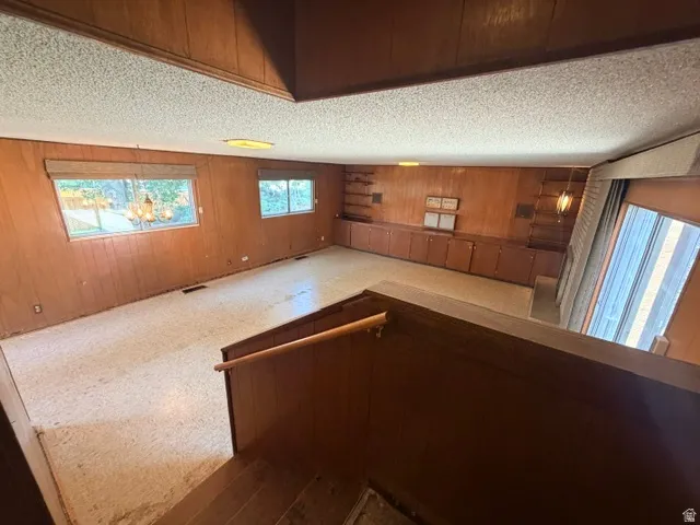 Spacious family room featuring wood paneling, built-in cabinetry, and integrated shelving  just a few steps down from the main floor level.