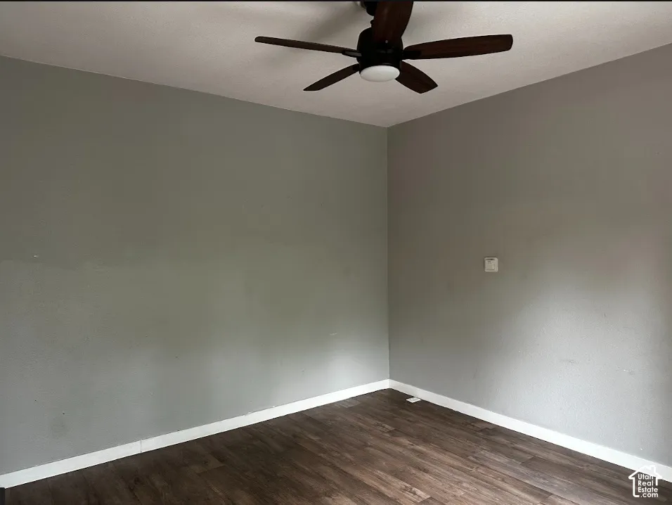 Wood-finish flooring with white trim and a ceiling fan